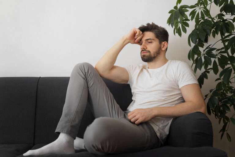 Tired father sitting on the edge of a sofa late at night, a sign of paternal burnout